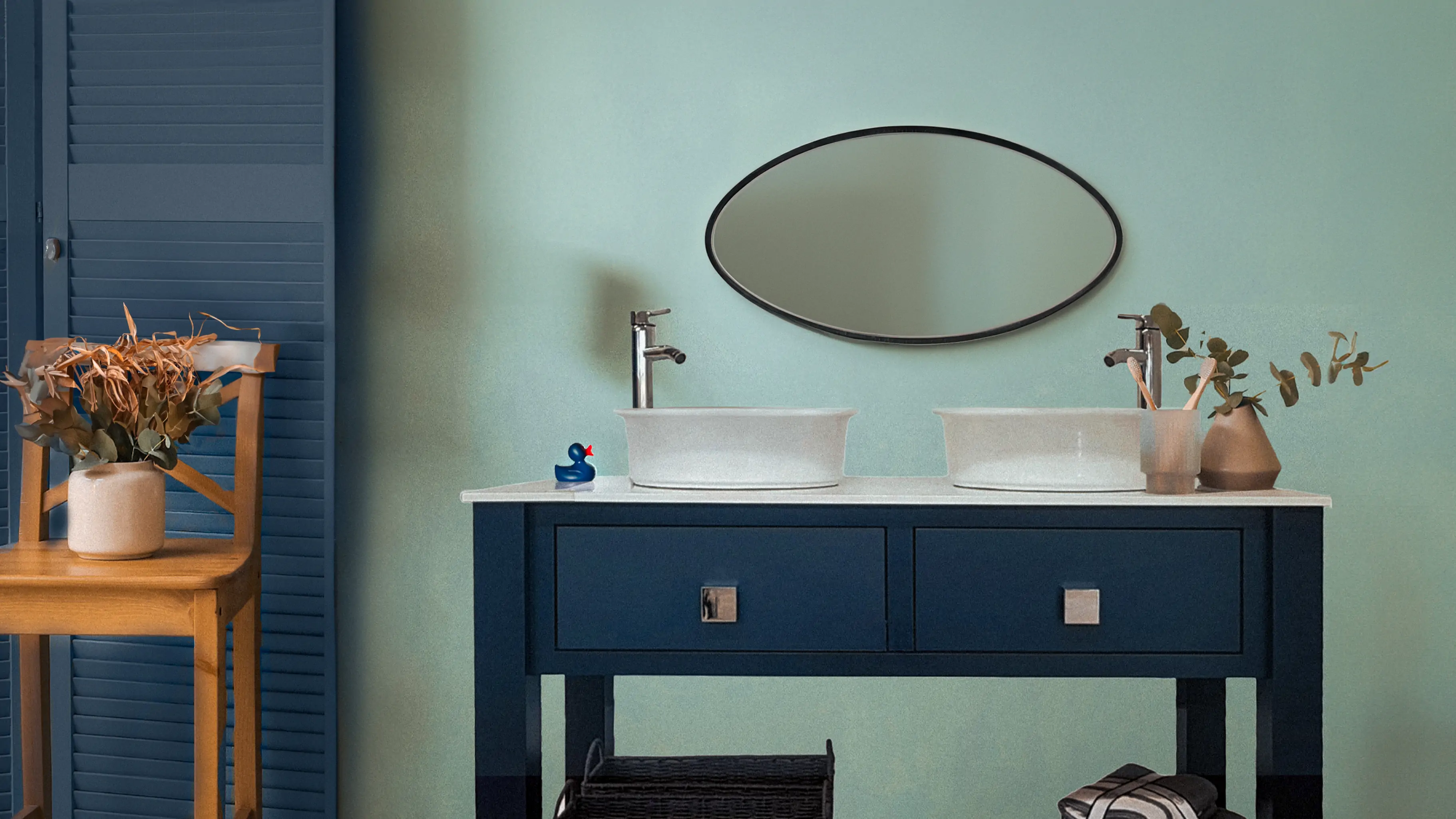 Green bathroom with a blue double basin vanity unit underneath a mirror, there is a small blue rubber duck next to the basin