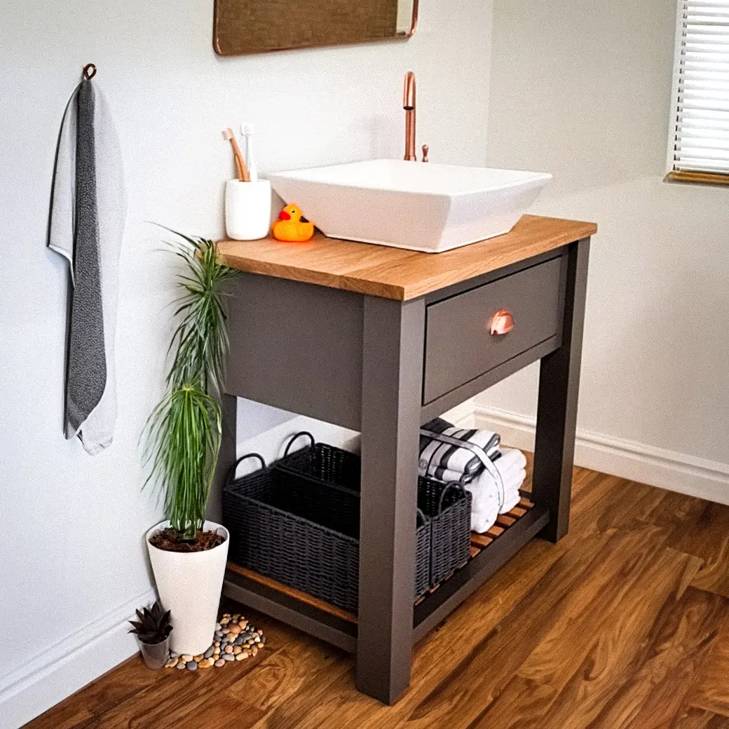 Single grey vanity unit in a white bathroom, a towel is hanging up next to it