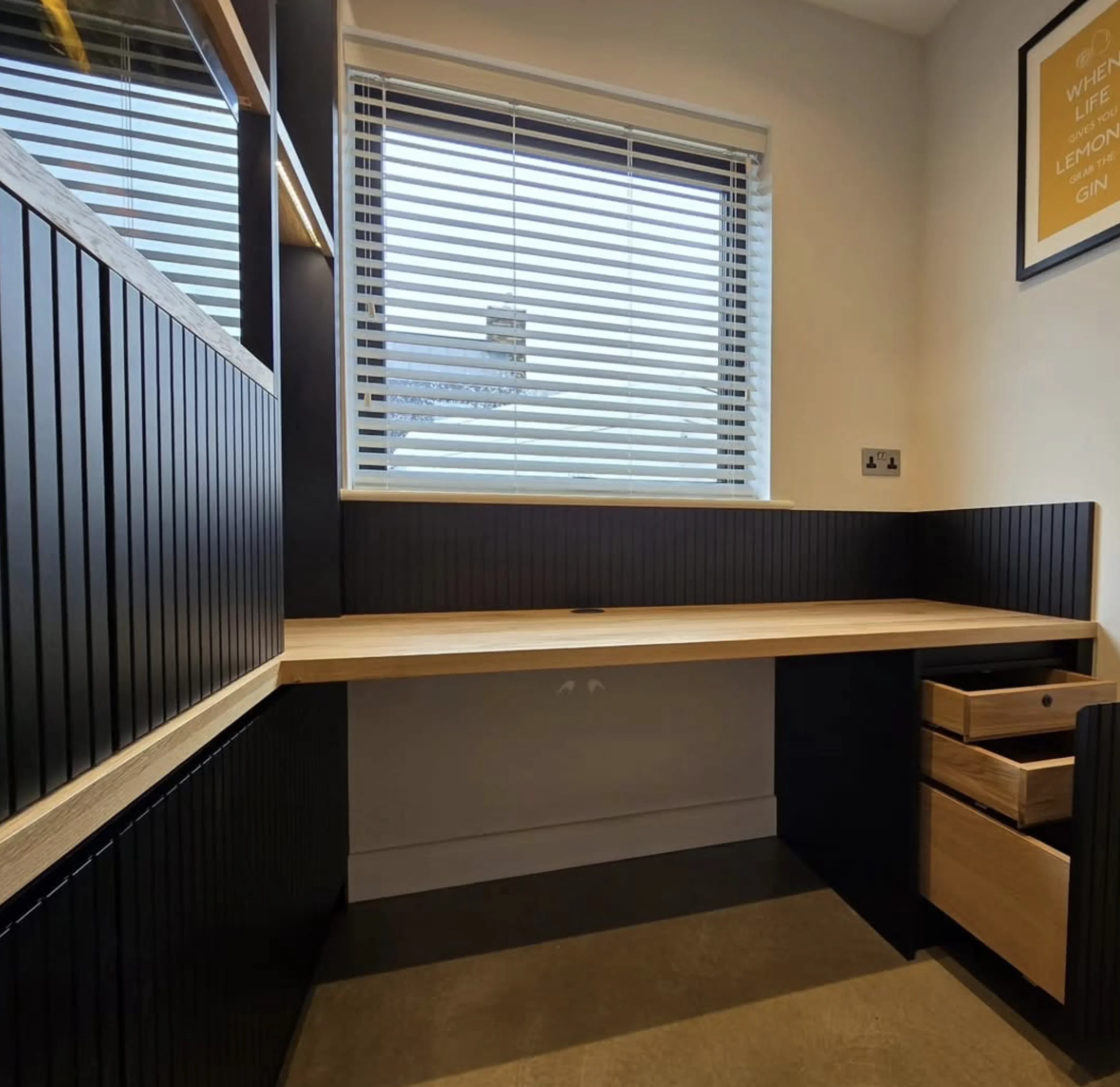 A bespoke oak desk with built-in drawers and dark fluted paneling