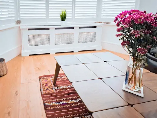 Living room  with a larger bay window, coffee table and a large elegantly design white radiator cover