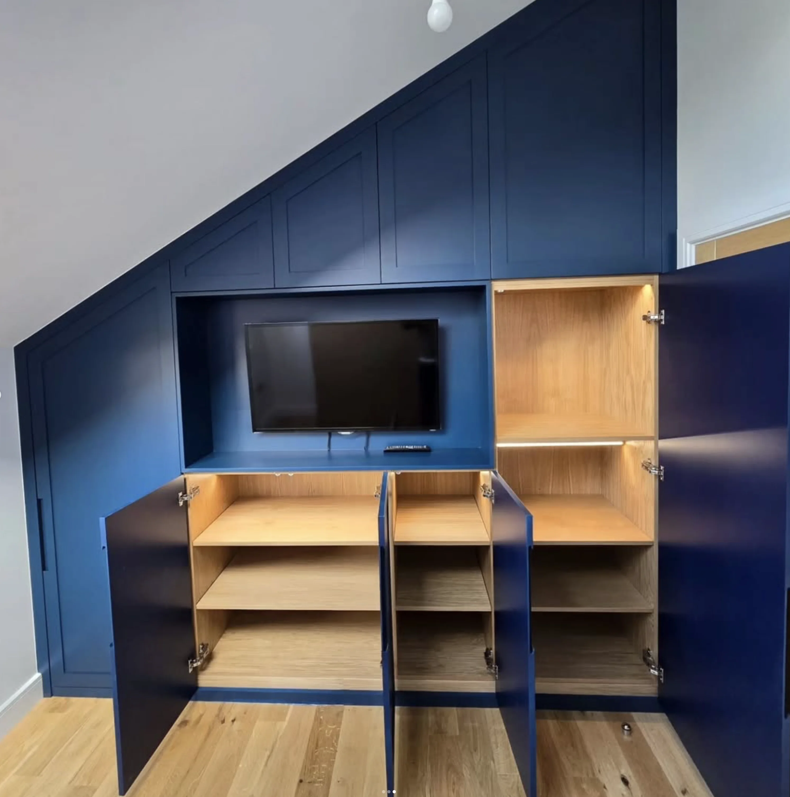 Fitted loft wardrobes with doors open revealing oak-lined interior shelving and storage