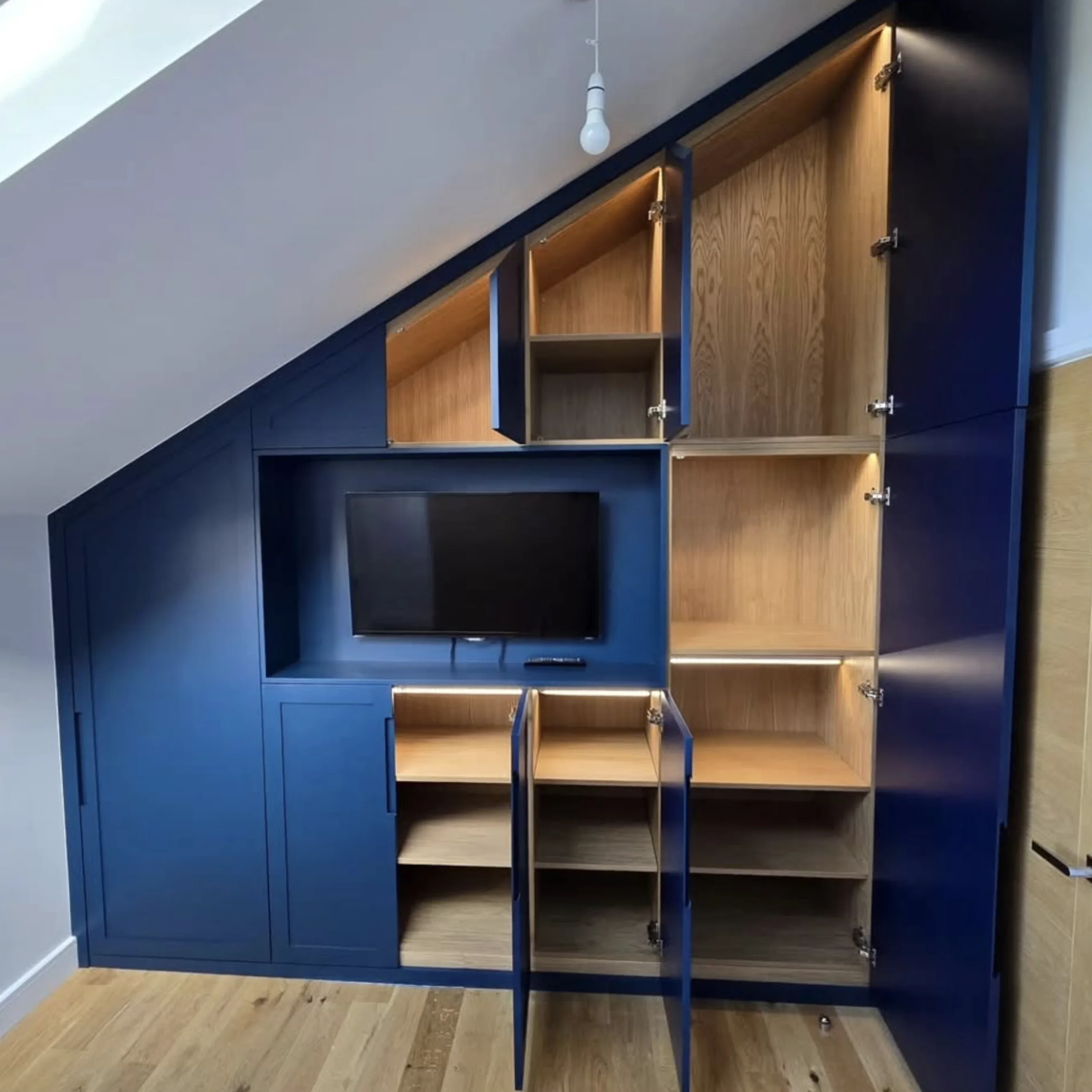 Full view of bespoke loft wardrobes with all doors open showing extensive oak storage