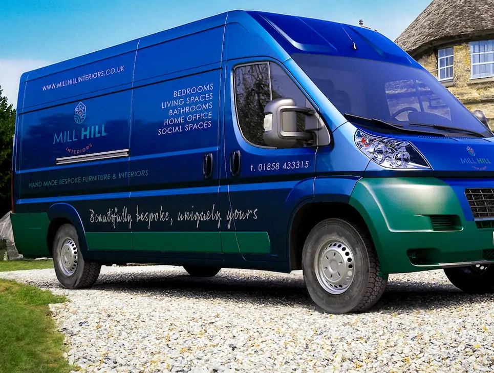 A Blue and green transit van with the mill hill logo on the side, parked in a drive way